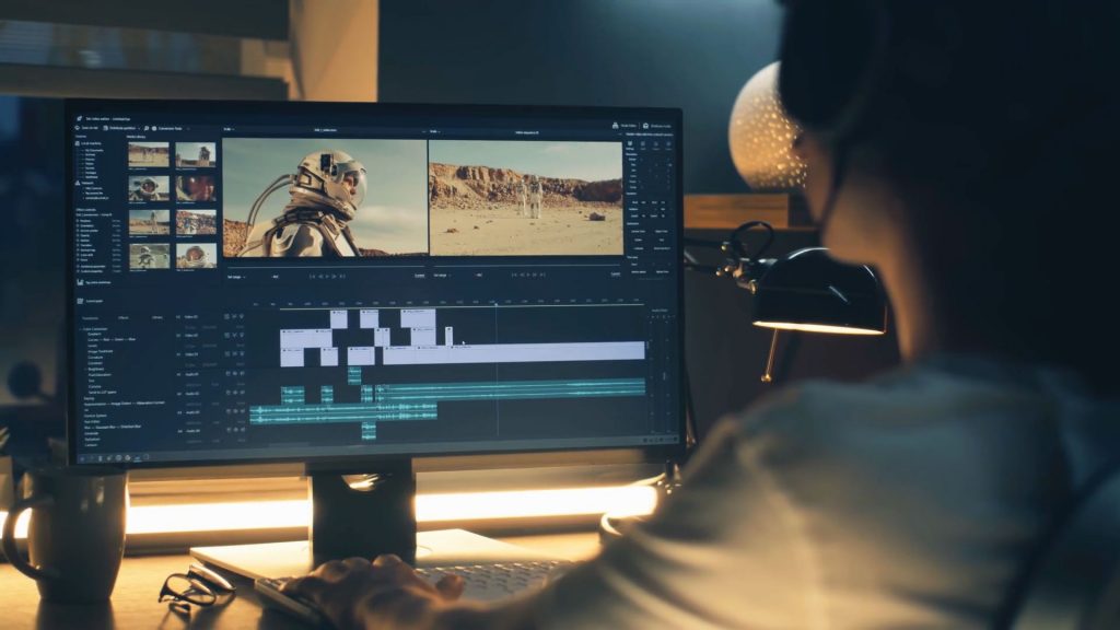 A video editor sitting at their desk setup and creating a video. They have multiple tracks and cuts all shown, which displays how in-depth editing can be.